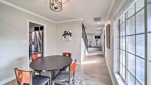 A modern kitchen with a stainless steel refrigerator, a dining table with chairs, and a staircase leading to an upper level. - Immaculate 'Woodland View' Retreat w/ Hot Tub (Tulsa)