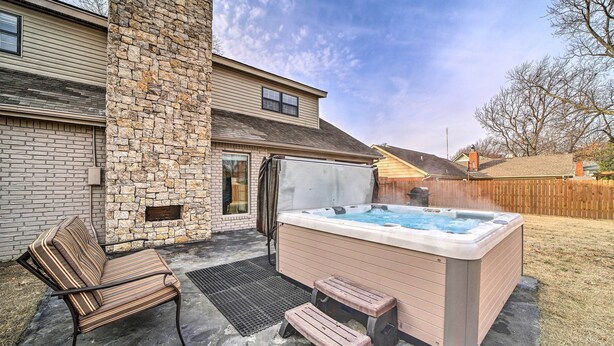 A hot tub with steps, a cushioned bench, and a stone wall. - Immaculate 'Woodland View' Retreat w/ Hot Tub (Tulsa)