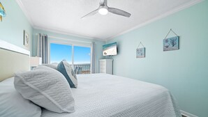 Ein Schlafzimmer mit Bett, Deckenventilator, Fernseher und einem Fenster mit Blick.