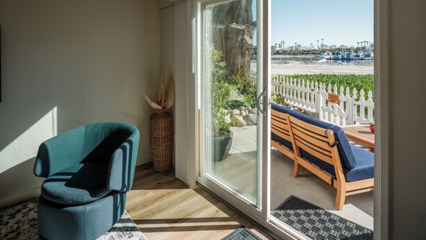 A room with a sliding glass door leading to an outdoor seating area with a bench and a view of a marina. - Waterfront Condo w/ AC, BBQ, & Outdoor Living (San Diego)