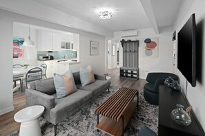 Una sala de estar moderna con un sofá gris, una mesa de centro de madera y un mueble de televisión negro.