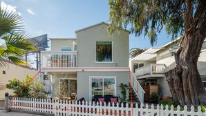 A two-story house with a balcony, a large tree, and a white picket fence. - Waterfront Condo w/ AC, BBQ, & Outdoor Living (San Diego)