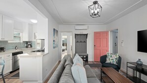 Et moderne køkken med hvide skabe, en central ø og et spiseområde med bænk.
