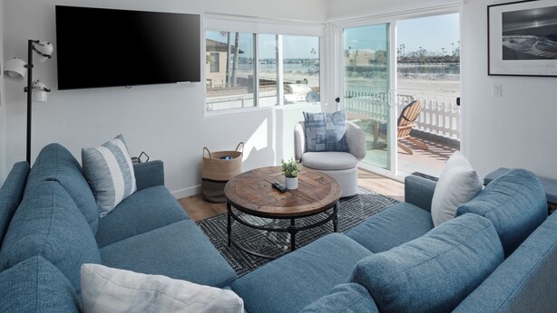 Een moderne woonkamer met een ruime zithoek, een flatscreen televisie en een balkon met uitzicht op het strand.