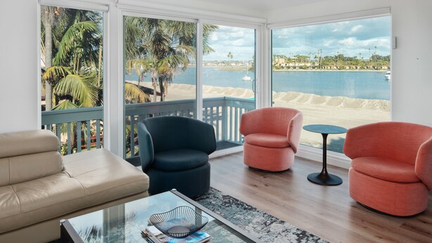 A living room with a view of the beach, two chairs, a sofa, and a coffee table. - Waterfront Condo | AC | Beach Toys | Walk to All! (San Diego)