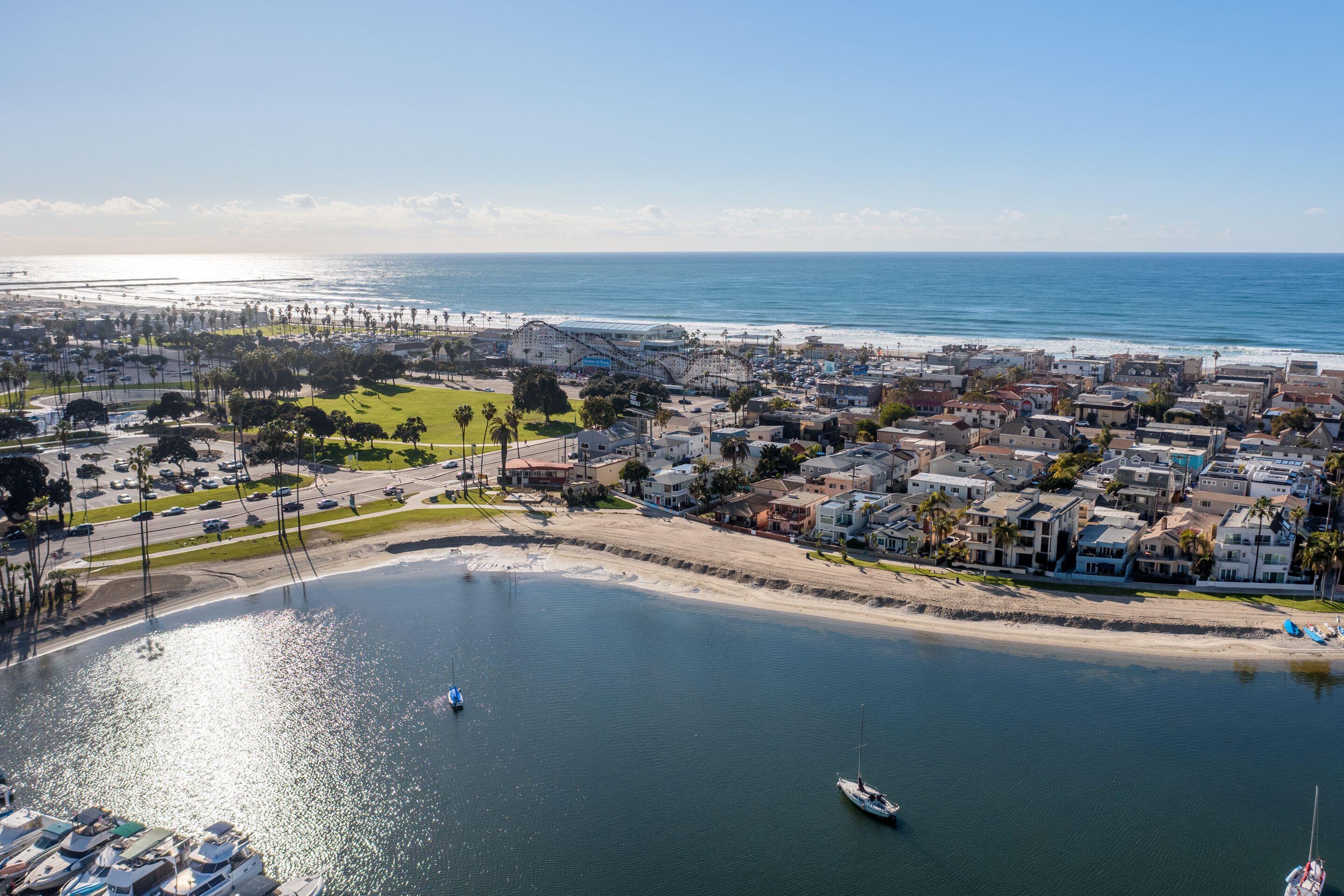 A coastal town with a marina, beachfront houses, and a clear view of the ocean.