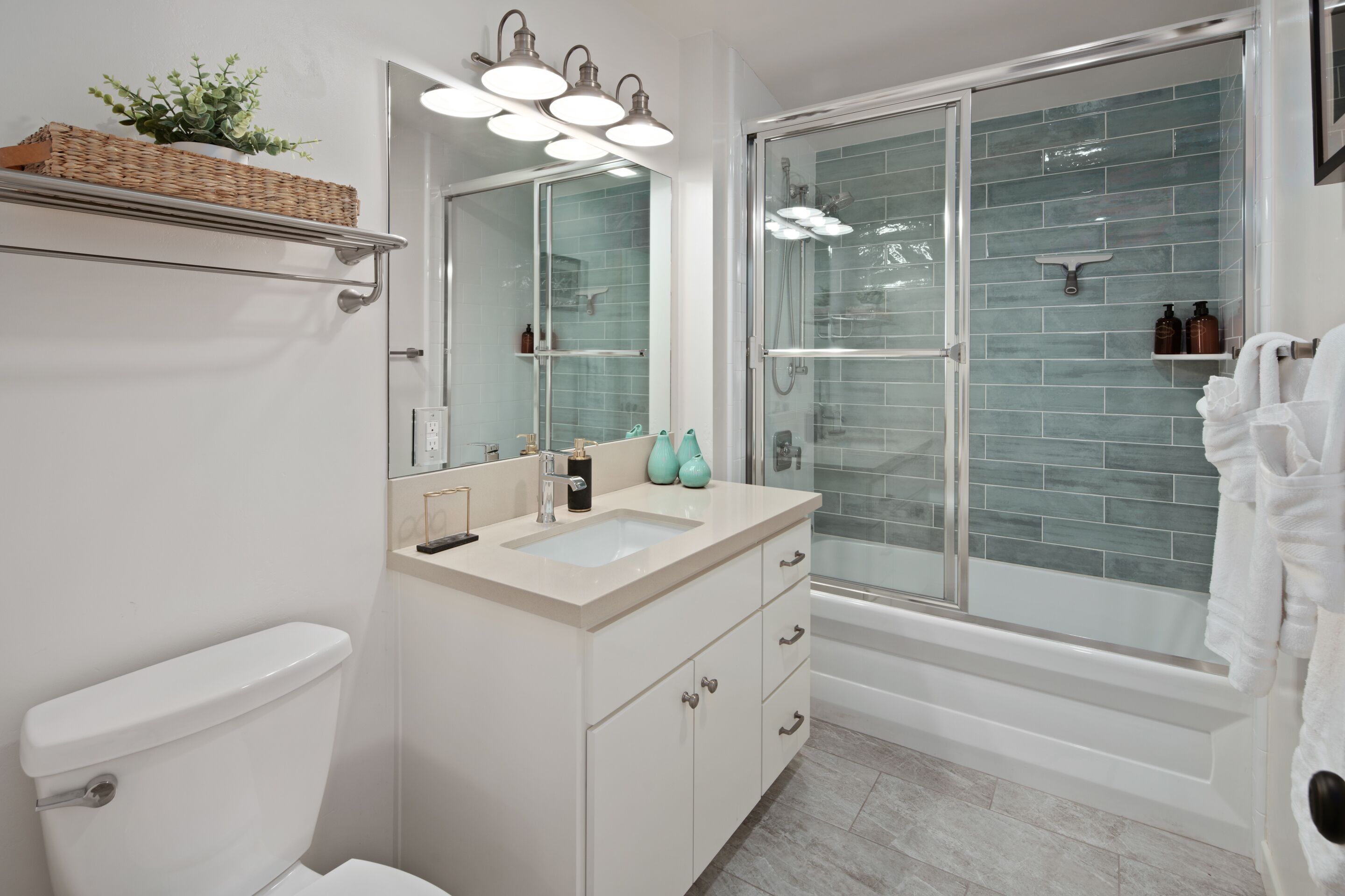 A modern bathroom with a white toilet, a beige sink, and a glass-enclosed shower.