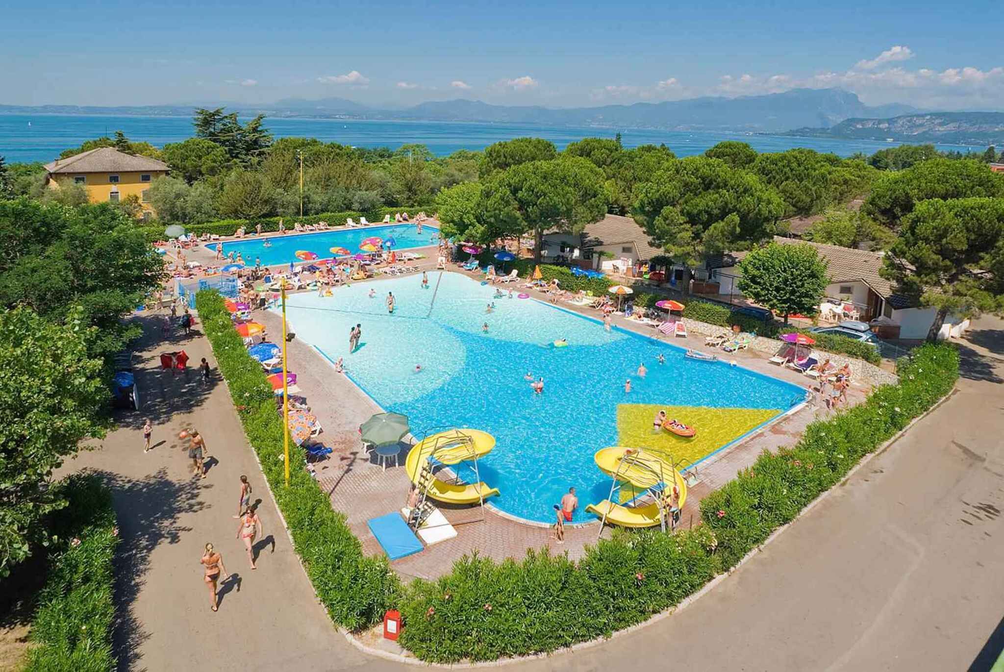 Ein großer Pool im Freien, umgeben von üppiger Vegetation und freiem Blick auf das Meer.
