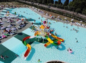 Una gran piscina al aire libre con múltiples toboganes y una zona de parque acuático.