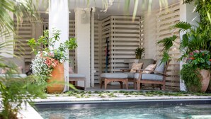 A poolside area with lounge chairs, a large planter with flowers, and a wooden fence. - Private pool, Luxury furnishings, Elevator, Short walk to beach & town (Folly Beach)