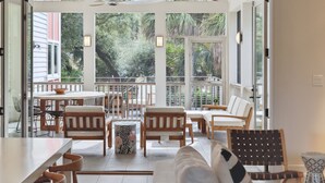 An open-plan living area with a balcony, furnished with sofas, chairs, and a dining table. - Private pool, Luxury furnishings, Elevator, Short walk to beach & town (Folly Beach)