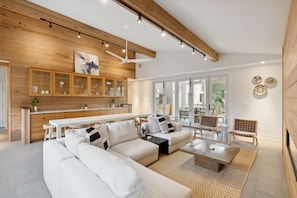 A modern living room with a sectional sofa, a coffee table, and a dining area with a white table and chairs.