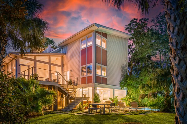 A modern two-story house with a covered patio, a staircase, and a pool.