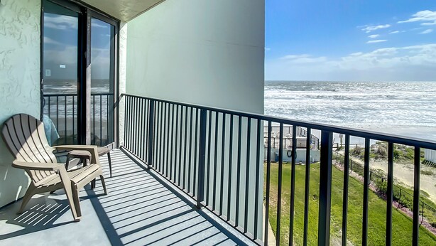 Ein Balkon mit Meerblick, einem Stuhl und einem Geländer.