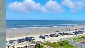 A beach view with a parking area and beach chairs. - 4th-Floor Oceanview Condo | Private Balcony, Oceanfront Pool & Beach Access (New Smyrna Beach)