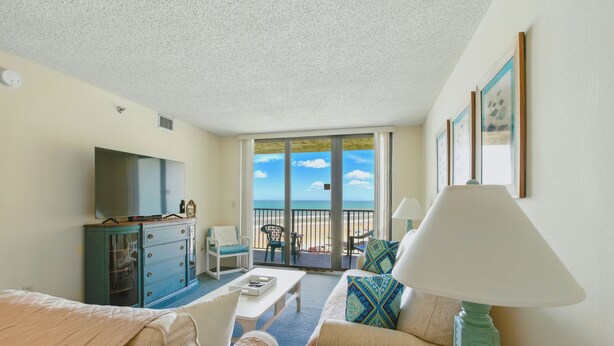 A hotel room with a balcony, a TV, a desk, and a sofa. - 4th-Floor Oceanview Condo | Private Balcony, Oceanfront Pool & Beach Access (New Smyrna Beach)