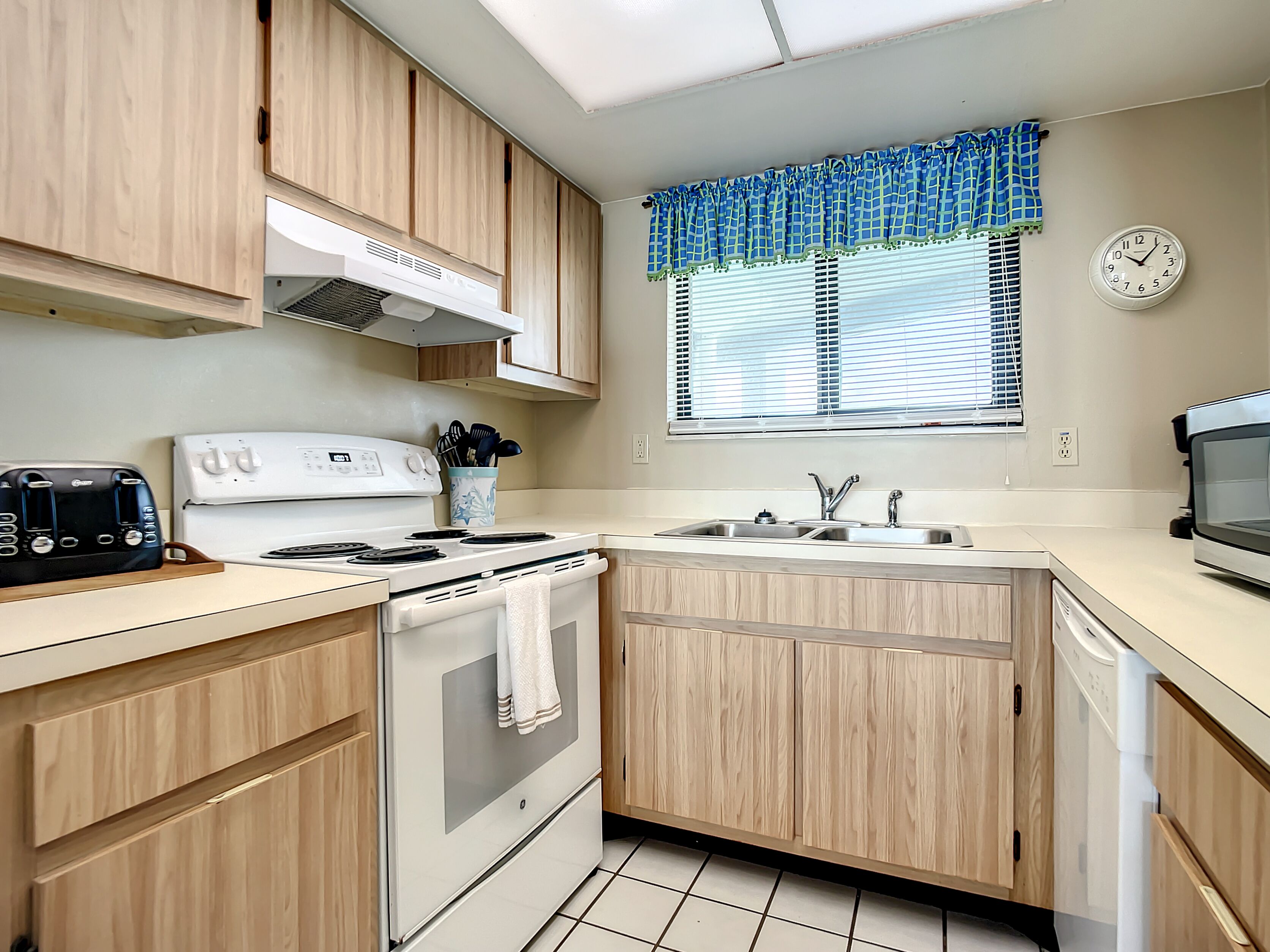 A kitchen with wooden cabinets, a white stove, a sink, and a microwave.