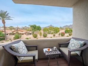 A balcony with two wicker chairs, a small table, and a view of a residential area with houses and trees. - Biltmore Bliss-Pool-Pickeball-Gym-Mountain views (Phoenix)