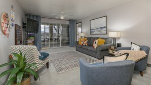 A living room with a grey sofa, blue armchairs, a patterned rug, and a ceiling fan. - Game-Time Getaway 3BR Family Condo w/ 3 baths + Patio | Champions 3-2 (Branson)