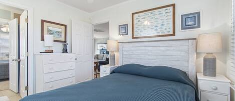 A bedroom with a bed, a nightstand, a dresser, a ceiling fan, and wall art.