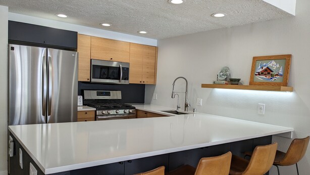 A modern kitchen with stainless steel appliances, a large island, and bar stools. - Modern Mountain Retreat in Frisco: Hot Tub, Fireplace, Views, Near Everything! (Frisco)