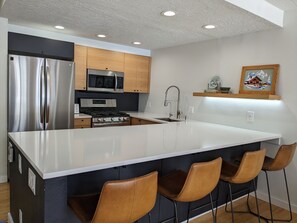 Enjoy meals and snacks at the kitchen island with a sink, stainless steel appliances, and wooden cabinets.