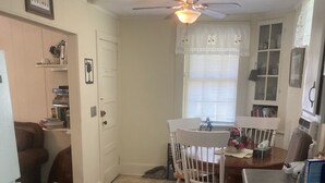 Une cuisine de taille réduite comprenant une table à manger, des chaises, une cuisinière et un ventilateur de plafond.