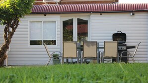 A house with a patio area featuring a grill, chairs, and a table. - Merala: cosy cottage with an easy stroll to CBD (Mudgee)