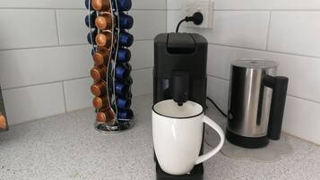 Keittiön työtaso, jossa on kahvinkeitin, muki ja pullonavaaja.
