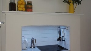 A kitchen with a clock, jars, and a plant. - Merala: cosy cottage with an easy stroll to CBD (Mudgee)