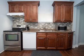Features a sleek range, dishwasher, and microwave, along with an oven and wooden cabinetry.