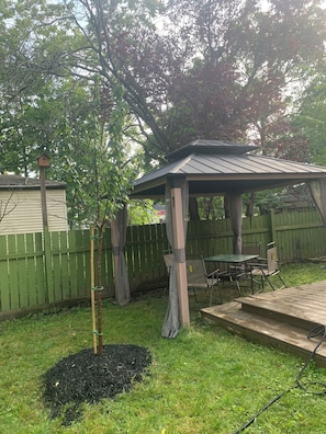 Relax in the serene backyard patio, surrounded by lush greenery and a wooden pergola.