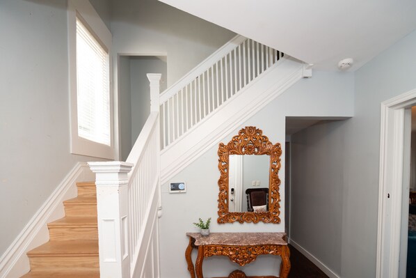 Staircase leads to an upper level, featuring a console table and ornate mirror.