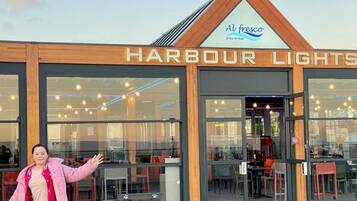 Een restaurant genaamd 'Harbour Lights' met een modern design, met grote ramen en een zichtbaar interieur met tafels en stoelen.