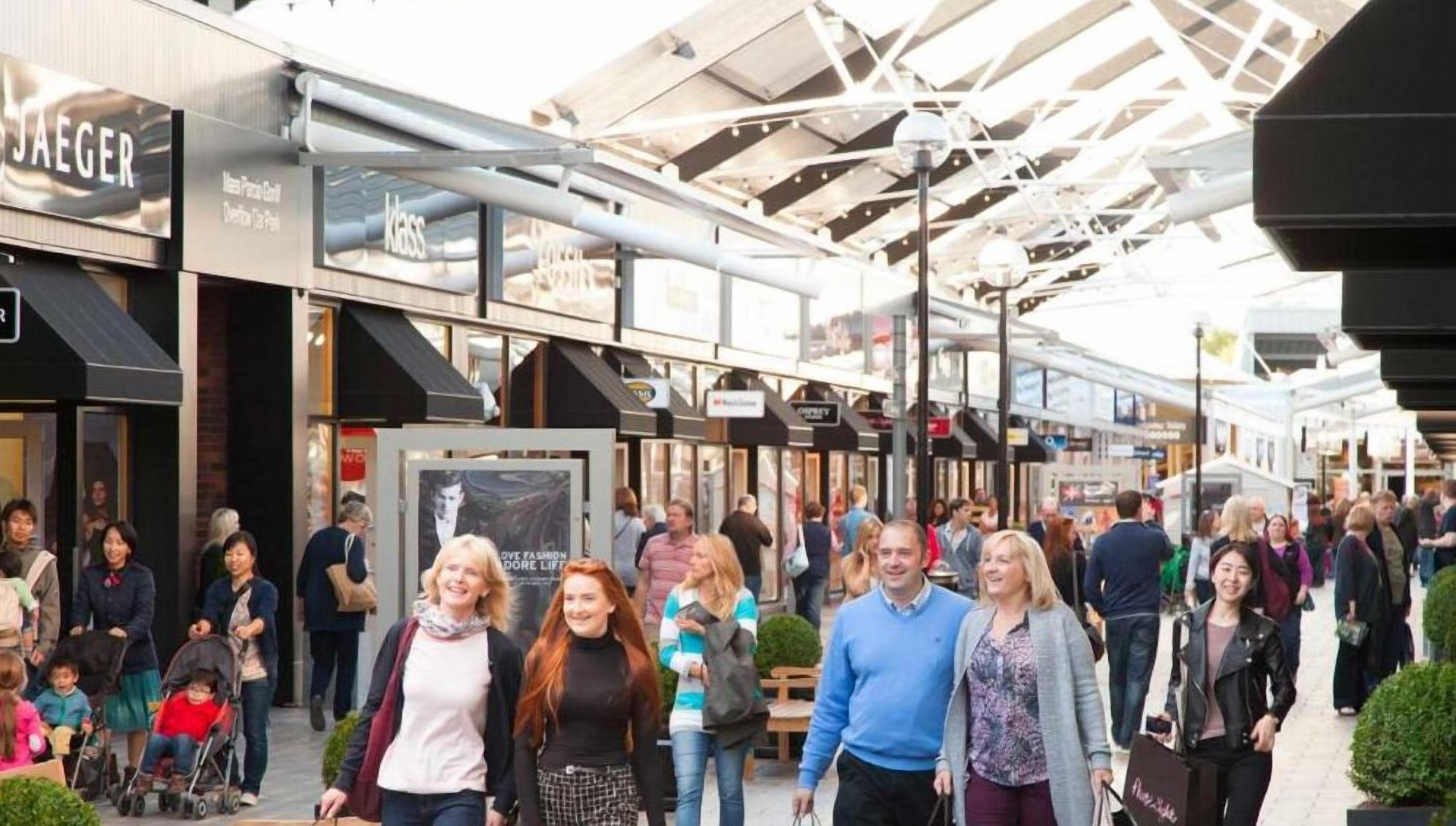 A busy pedestrian walkway with various storefronts, including a visible 'JAEGER' sign.