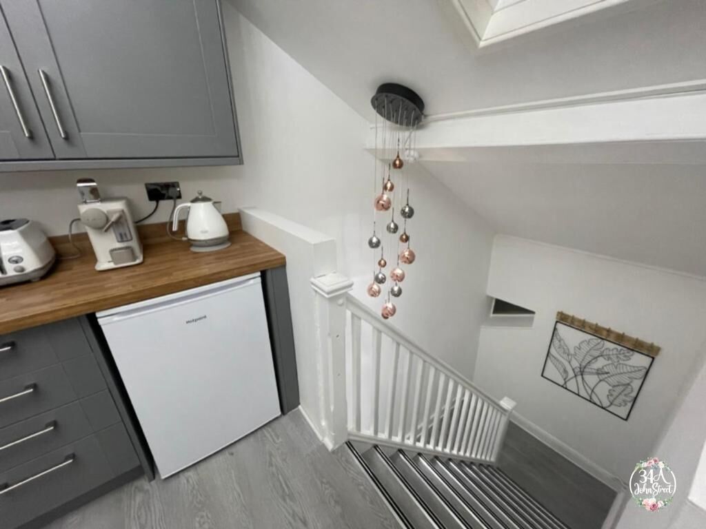 A kitchen with a white refrigerator, a coffee maker, and a toaster on a wooden countertop.