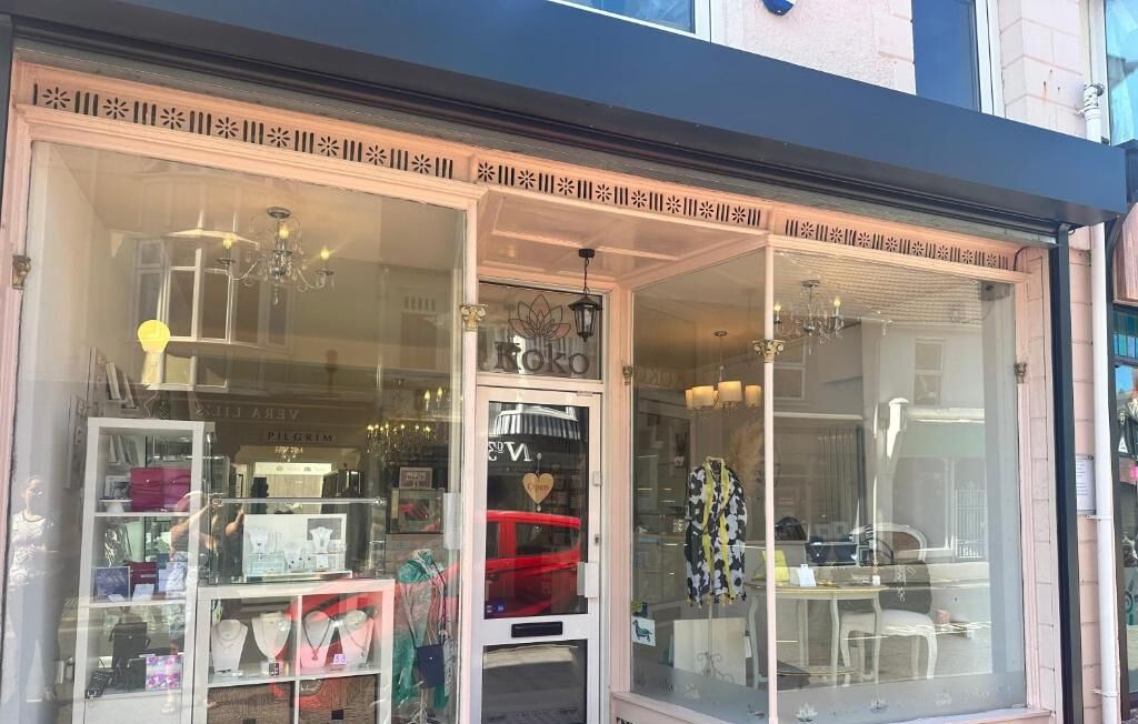 Een juwelenwinkel met glazen vitrines en een rode stoel in het midden.