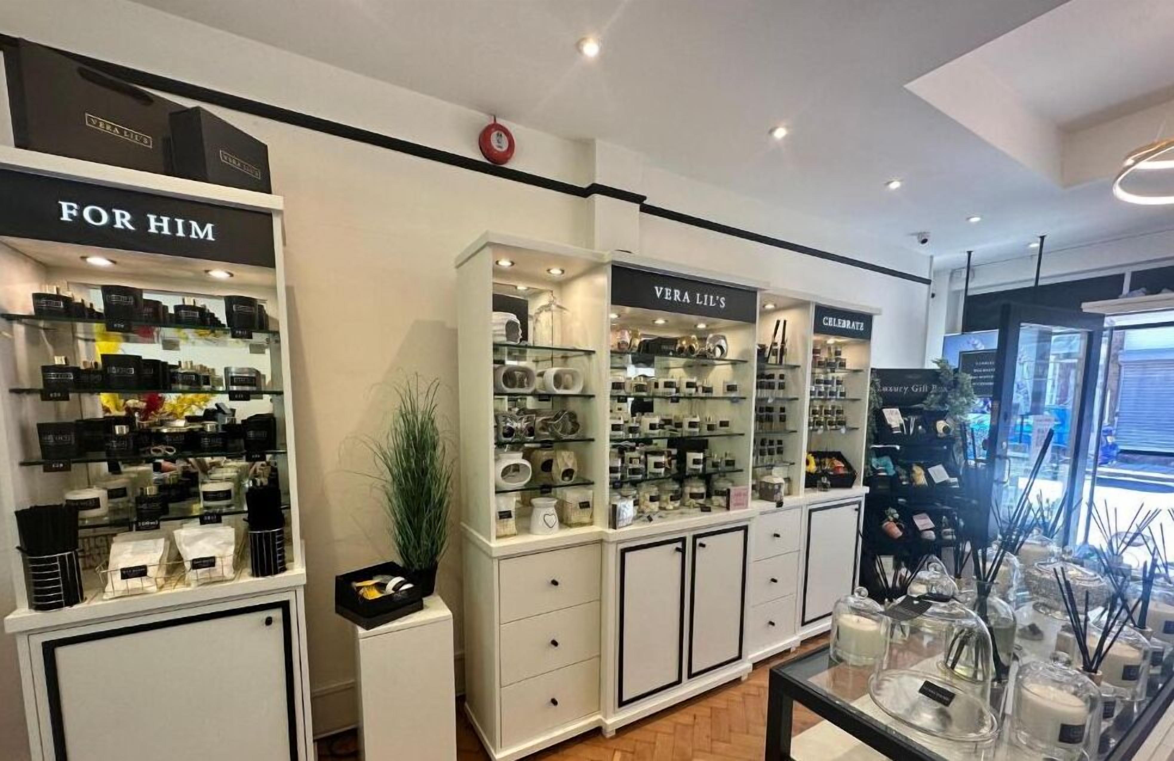 A store with shelves of perfumes and other personal care items, a section labeled "FOR HIM," and another labeled "VERA LIL'S."