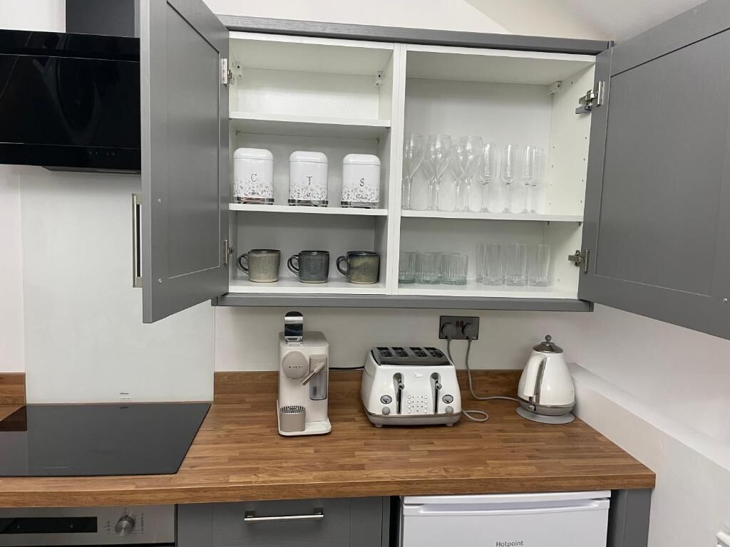 Une cuisine équipée d’un four à micro-ondes, d’un grille-pain et d’une bouilloire intégrés, le tout posé sur un plan de travail en bois.