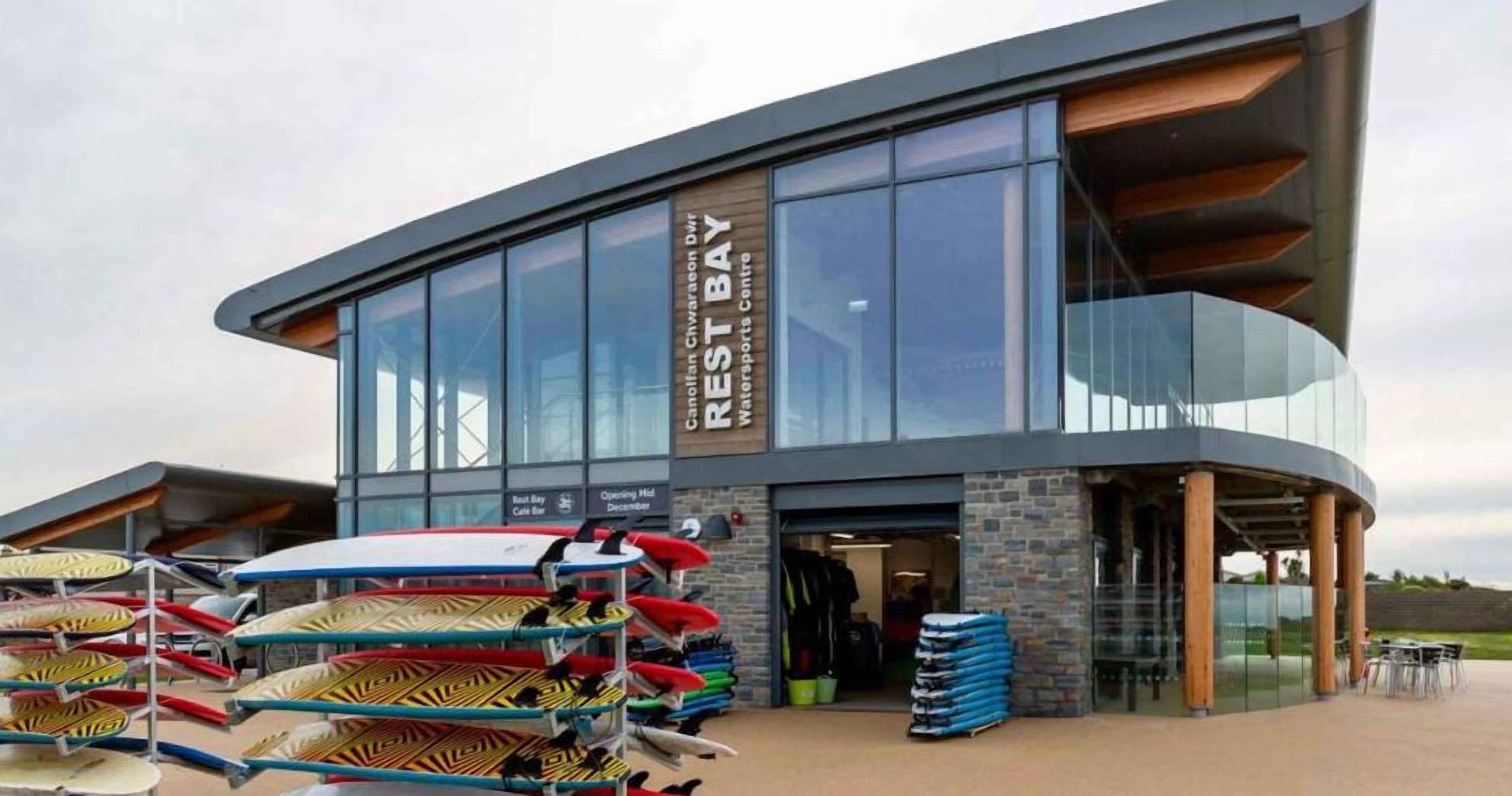 A modern building with a sign reading "Rest Bay Watersports Centre."