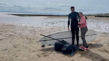Una playa con una tabla de surf y bolsas en la arena.