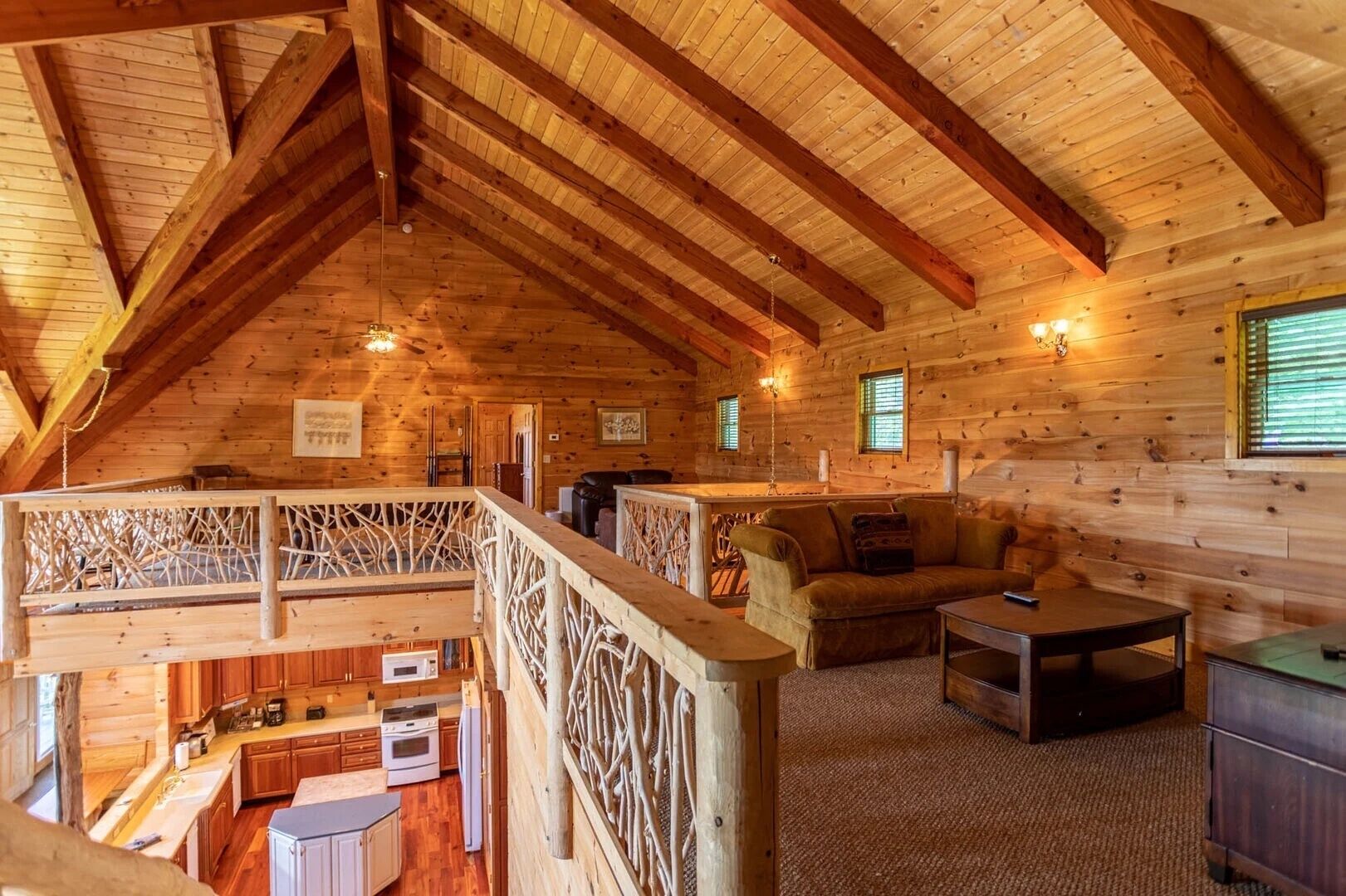 Een houten chalet met slaapkamer op de zolder, een eethoek en een woonkamer met een bank en salontafel.