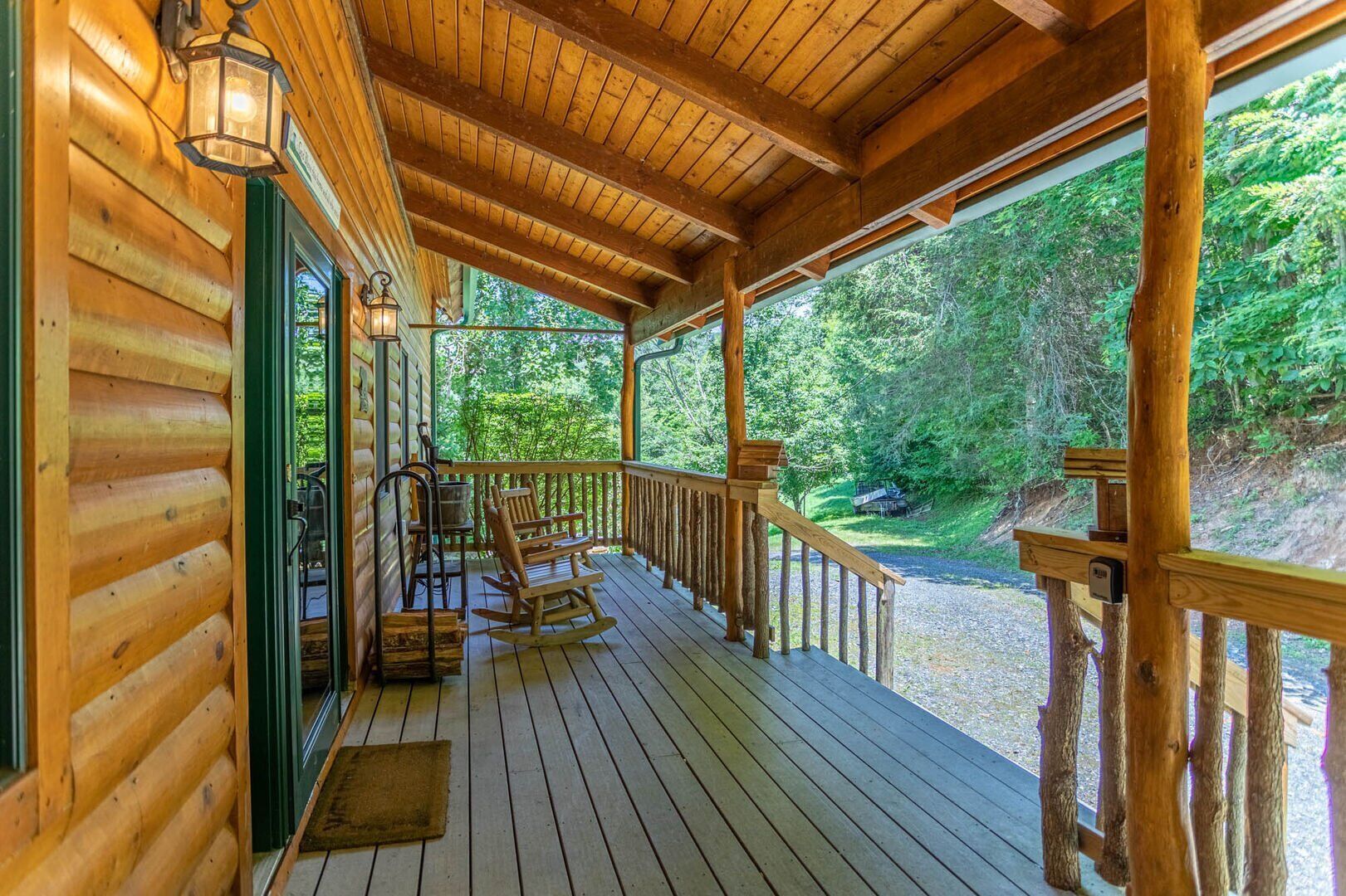A wooden cabin with a porch, rocking chairs, and a view of the forest.