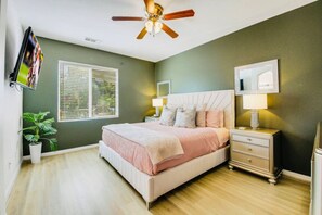 A bedroom with a bed, bedside tables, a ceiling fan, a window with blinds, and a potted plant. - Flairbnb/Pool/Spa/Pool Table (Indio)