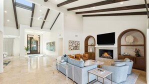 Amplia sala de estar con chimenea, muebles modernos y un televisor grande.