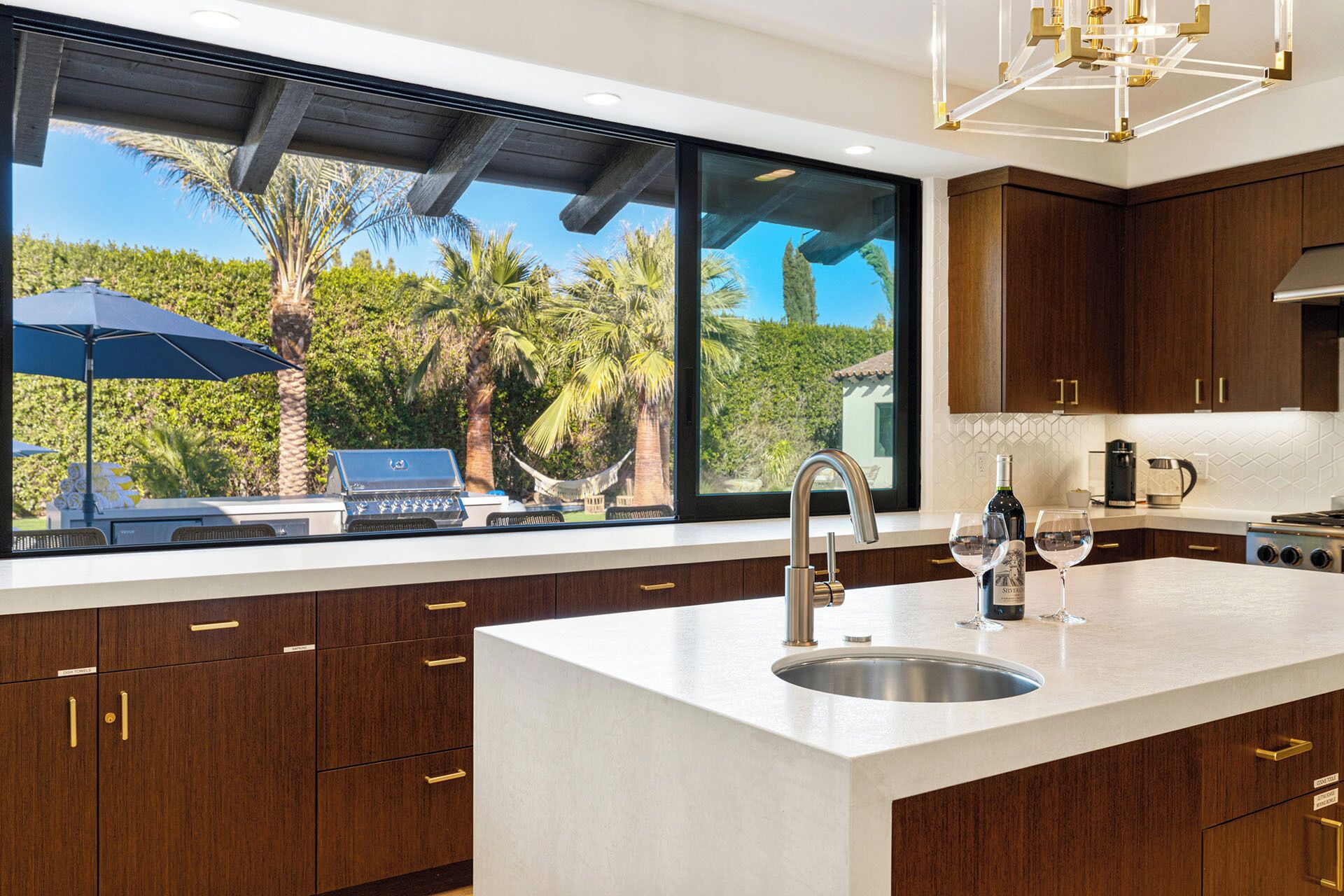 Una cocina moderna con una isla grande, pileta de acero inoxidable y muebles de madera.