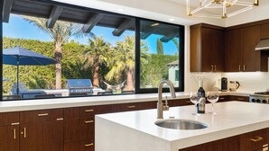 Una cocina moderna con una isla grande, pileta de acero inoxidable y muebles de madera.