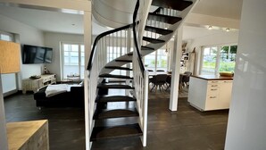 Ein modernes Interieur mit einer Wendeltreppe, einem Essbereich und Blick ins Freie.