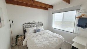 Un dormitorio con cama, ventana y perchero.