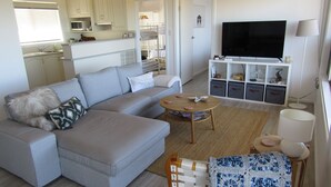 Una sala de estar moderna con un sofá seccional gris, una mesa de centro de madera y un mueble de televisión con espacio de almacenamiento.